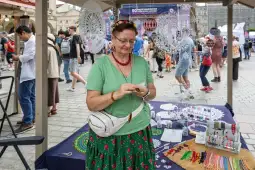 Kobieta w tradycyjnym stroju ludowym sprzedaje rękodzieło na festiwalu.
