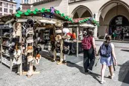 Stoiska z futrzanymi czapkami i akcesoriami na rynku. Dwie osoby spacerują obok.