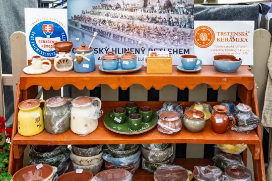 Stojak z ceramiką, w tym garnki i miski, na tle plakatu z festiwalu.