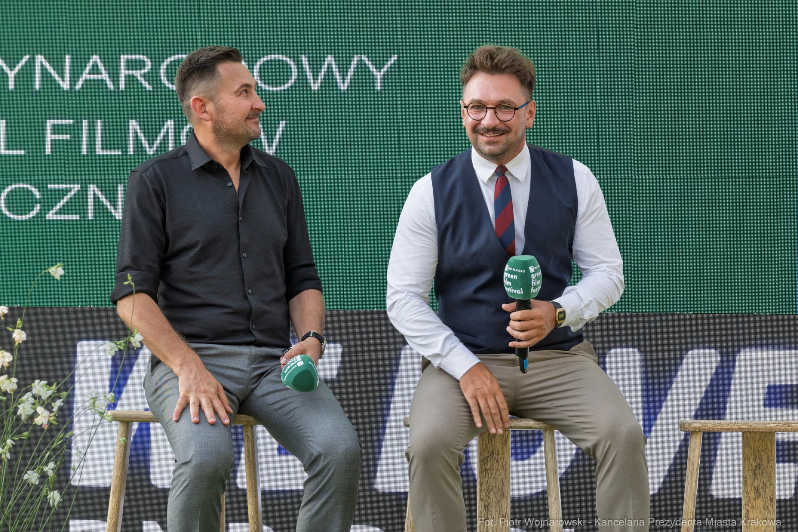Dwóch mężczyzn siedzących na stołkach, rozmawiających podczas wydarzenia filmowego.  Autor: Piotr Wojnarowski