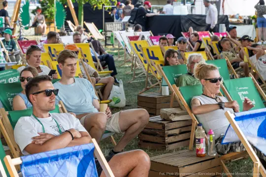 Ludzie siedzący na leżakach podczas wydarzenia plenerowego.