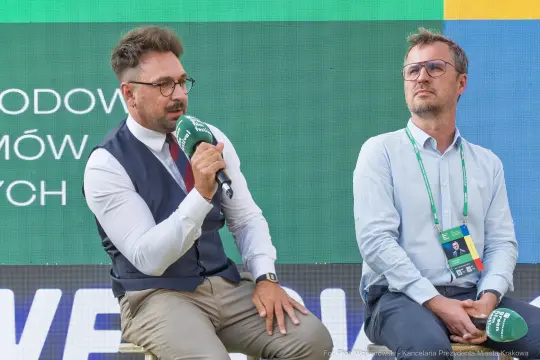 Dwóch mężczyzn w garniturach podczas dyskusji na konferencji.