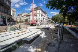 Prace budowlane na ulicy, widoczne maszyny i materiały budowlane.