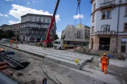 Budowa ulicy z ciężkim sprzętem, robotnikami i materiałami budowlanymi.