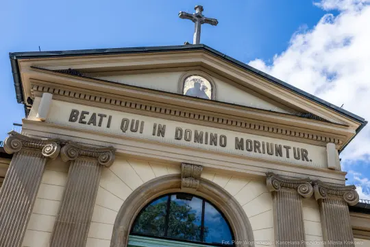 Fasada budynku z napisem "BEATI QUI IN DOMINO MORIUNTUR" i krzyżem na szczycie.