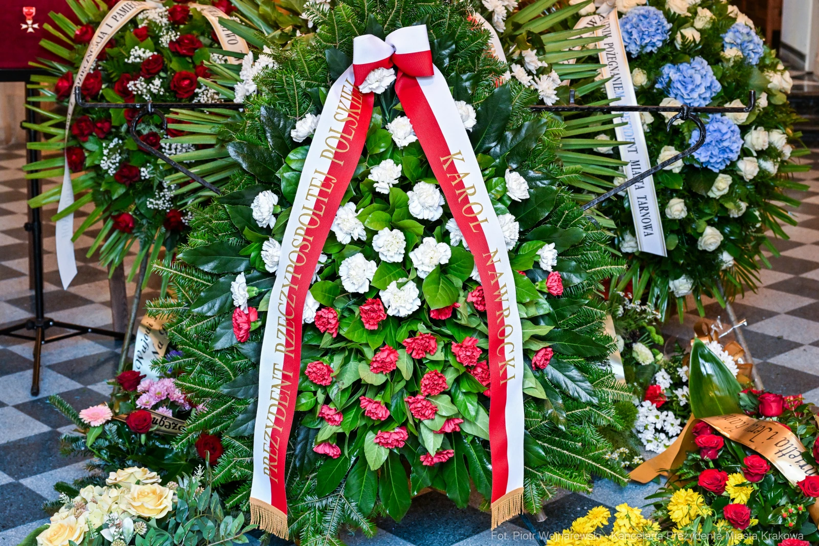 Wieniec z czerwonymi i białymi kwiatami oraz wstęgami z napisami.  Autor: Piotr Wojnarowski