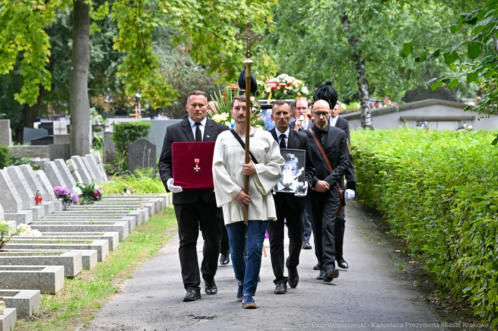 Pochód żałobny z osobami niosącymi sztandar i zdjęcie zmarłego na cmentarzu.  Autor: Piotr Wojnarowski