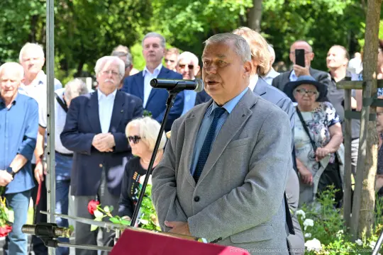 Mężczyzna przemawia do zgromadzonego tłumu podczas uroczystości na świeżym powietrzu.