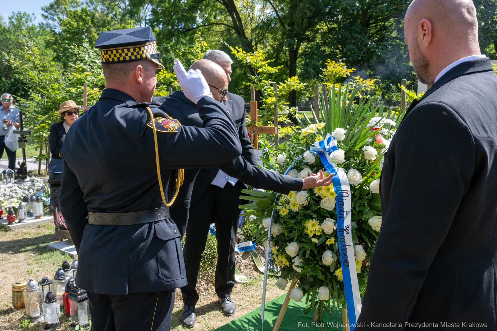 Ceremonia pogrzebowa z obecnością strażnika i kwiatów na grobie.  Autor: Piotr Wojnarowski