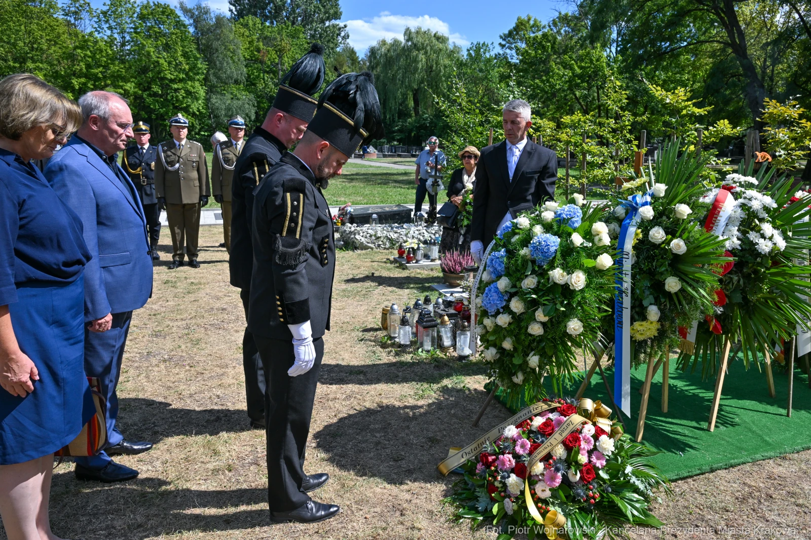 Ceremonia złożenia kwiatów na grobie, uczestnicy w mundurach i eleganckich strojach.  Autor: Piotr Wojnarowski