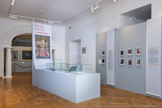 Wystawa sztuki w muzeum z eksponatami w szklanych gablotach i informacjami na ścianach.