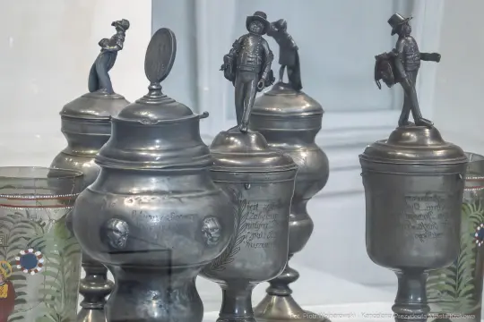 Srebrne kufle z figurkami, zdobione inskrypcjami i malowidłami.