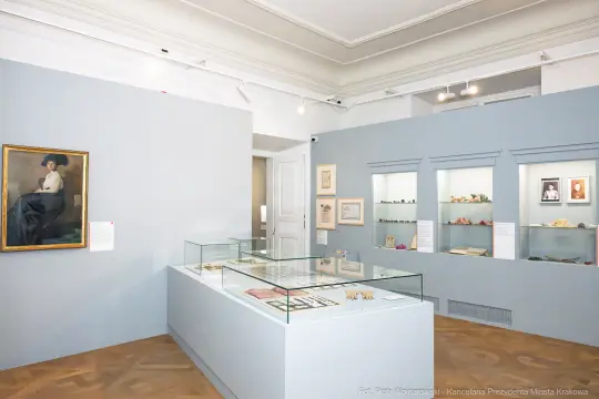 Wnętrze muzeum z wystawą eksponatów i obrazem na ścianie.