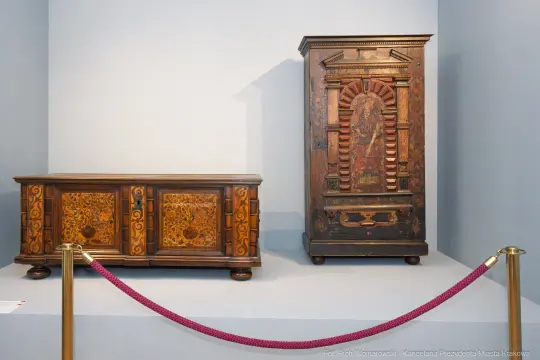 Meble z ornamentami w stylu ludowym, drewniana szafka i wysoka szafa.