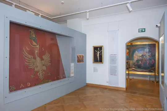 Zabytkowa flaga z orłem, eksponaty w muzeum, obrazy na ścianach.