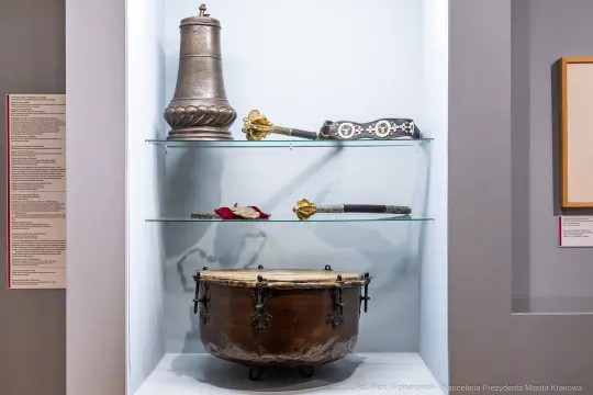 Zestaw historycznych instrumentów muzycznych i przedmiotów dekoracyjnych w witrynie.