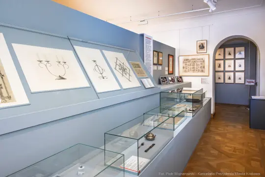 Ekspozycja w muzeum z rysunkami i artefaktami w szklanych gablotach.