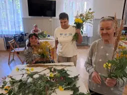 Kobiety trzymają bukiety kwiatów w jasnym pomieszczeniu.