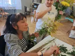 Kobiety pracują nad tworzeniem bukietów z kwiatów i ziół.