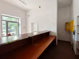 Pusty lokal z drewnianą ladą i oknem, obok żółta skrzynka.