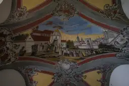 Fresk z postaciami i architekturą, przedstawiający scenę z życia codziennego.