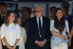 Grupa osób w eleganckich strojach podczas uroczystości.