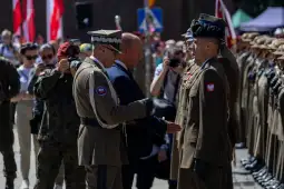 Ceremonia wojskowa z udziałem żołnierzy i oficjeli, w tle tłum widzów.