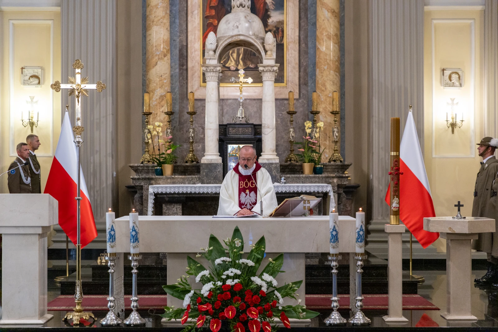 Msza święta w kościele z flagami Polski i dekoracjami kwiatowymi.  Autor: Bogusław Świerzowski