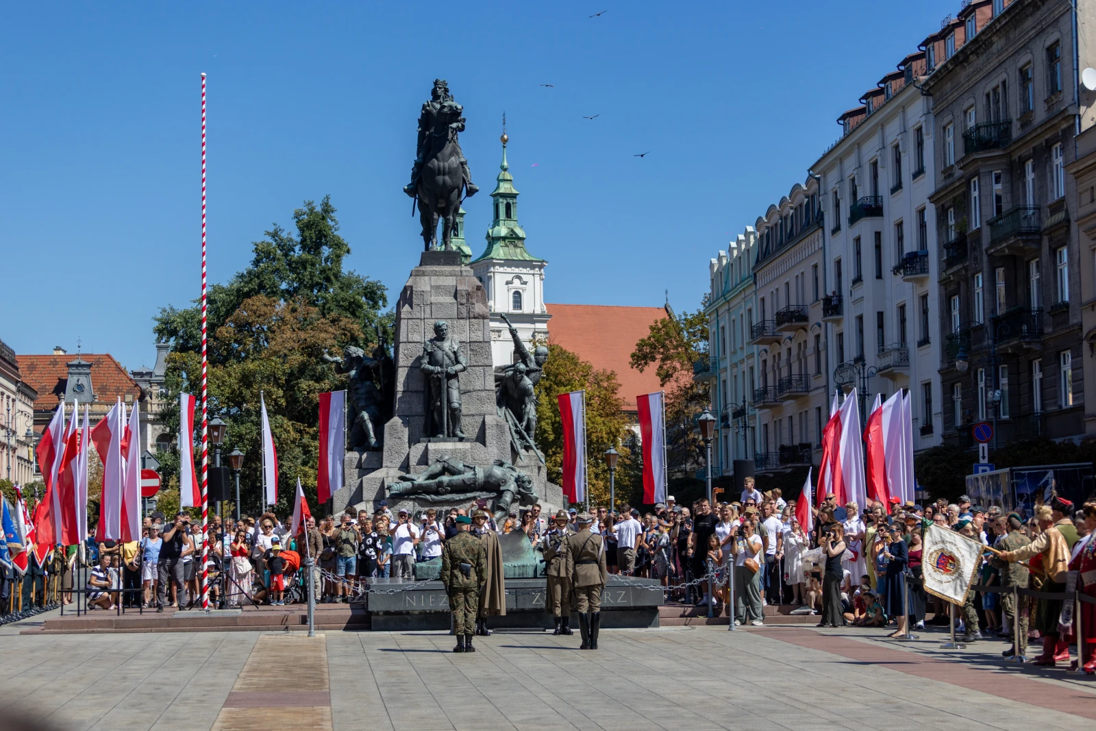 Uroczystość z udziałem żołnierzy i tłumu ludzi przy pomniku w centrum miasta. Flagi narodowe w tle.  Autor: Bogusław Świerzowski