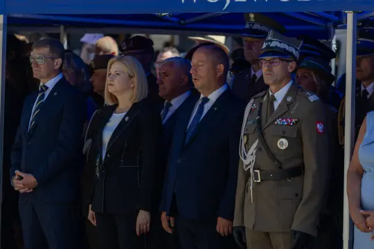Uczestnicy ceremonii wojskowej w strojach formalnych, w skupieniu podczas uroczystości.