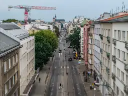 Ulica z widokiem na budynki, drzewa i dźwig w tle.