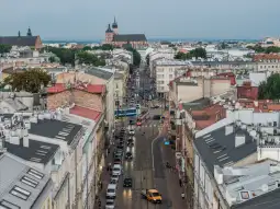 Widok na ulicę z zabudową miejską i kościołem w tle.
