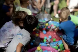 Dzieci bawią się w basenie z kolorowymi piłkami.