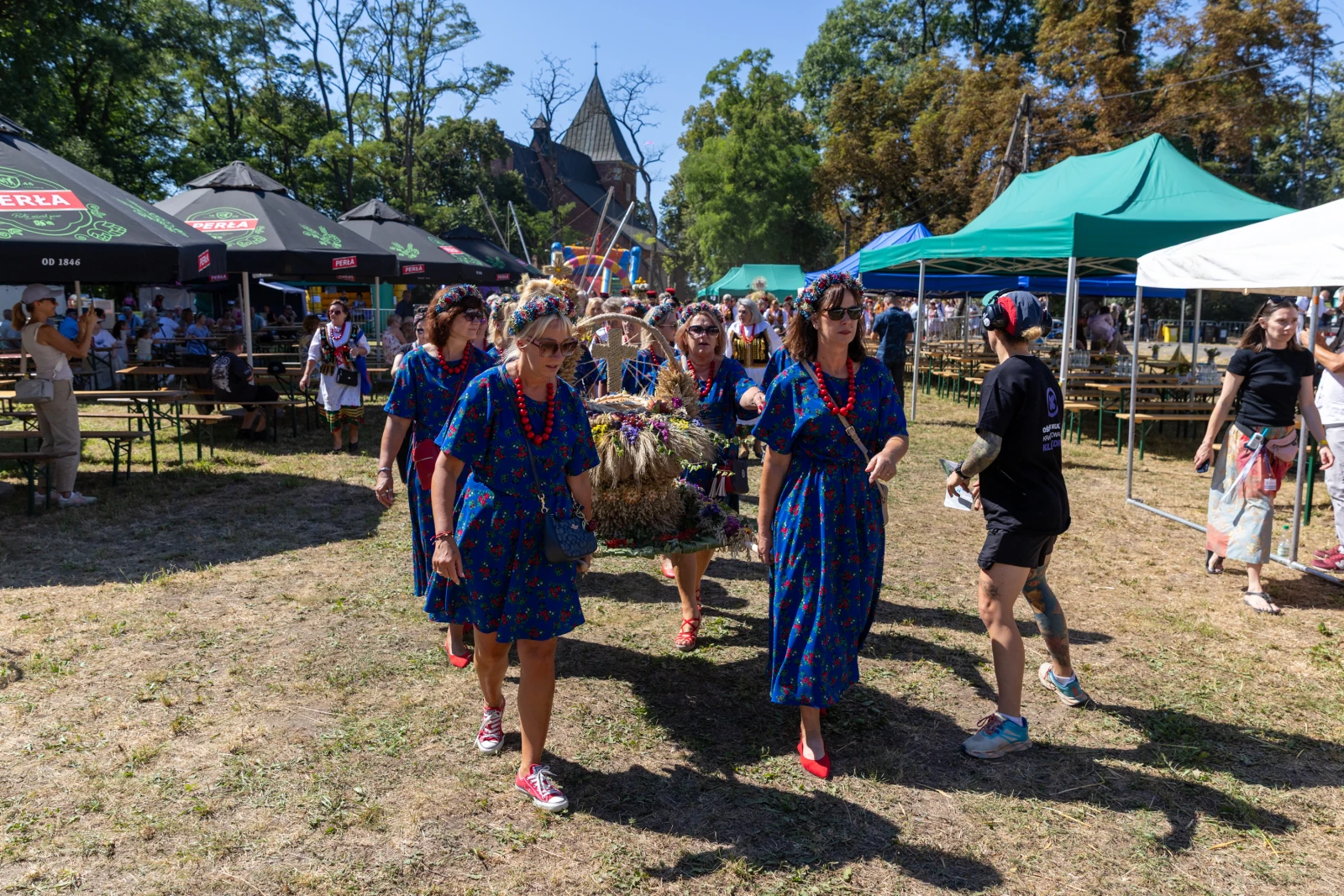 Grupa kobiet w kolorowych sukienkach niesie tradycyjną dekorację podczas festiwalu.  Autor: Bogusław Świerzowski