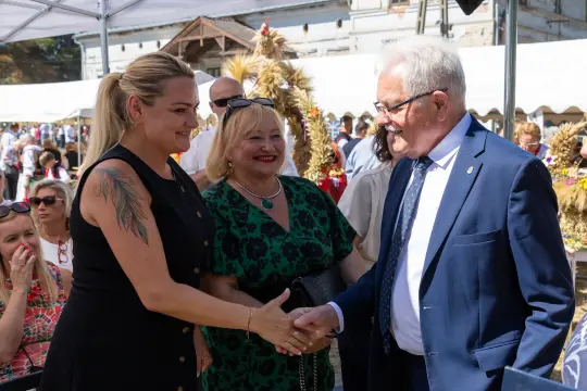 Spotkanie dwóch kobiet z mężczyzną, uściski dłoni, radosna atmosfera.