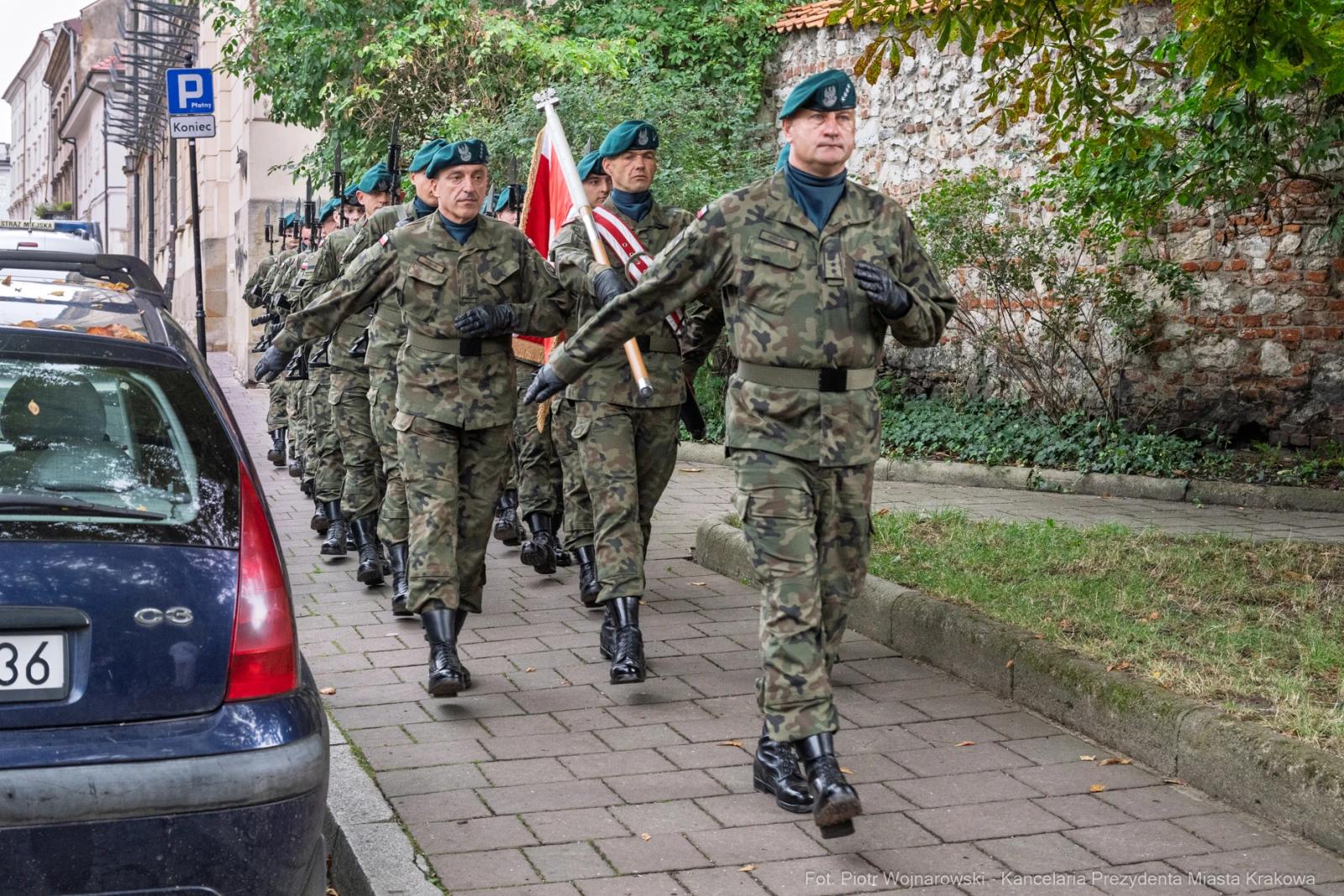Żołnierze w mundurach wojskowych maszerują ulicą, niosąc flagę.  Autor: Piotr Wojnarowski