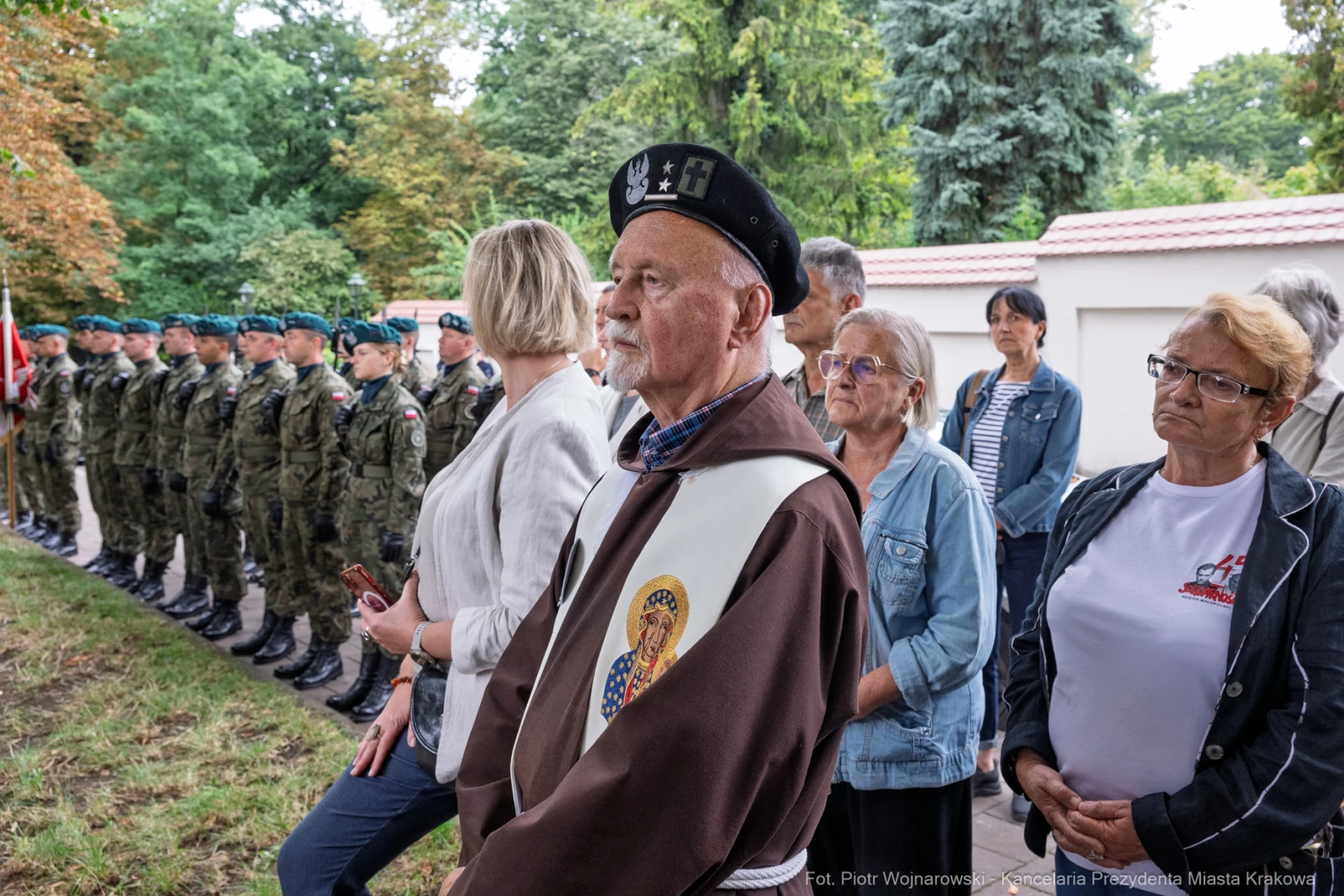 Uczestnicy ceremonii, w tym weteran, stoją wśród żołnierzy i innych osób.  Autor: Piotr Wojnarowski
