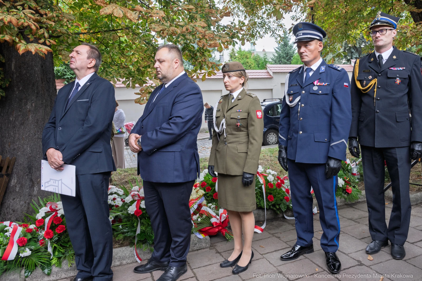 Uczestnicy ceremonii złożenia kwiatów, w mundurach i garniturach, przy pomniku.  Autor: Piotr Wojnarowski