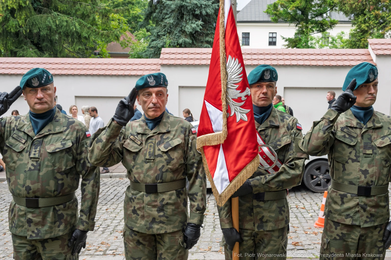 Czterech żołnierzy w mundurach wojskowych salutujących z flagą Polski.  Autor: Piotr Wojnarowski