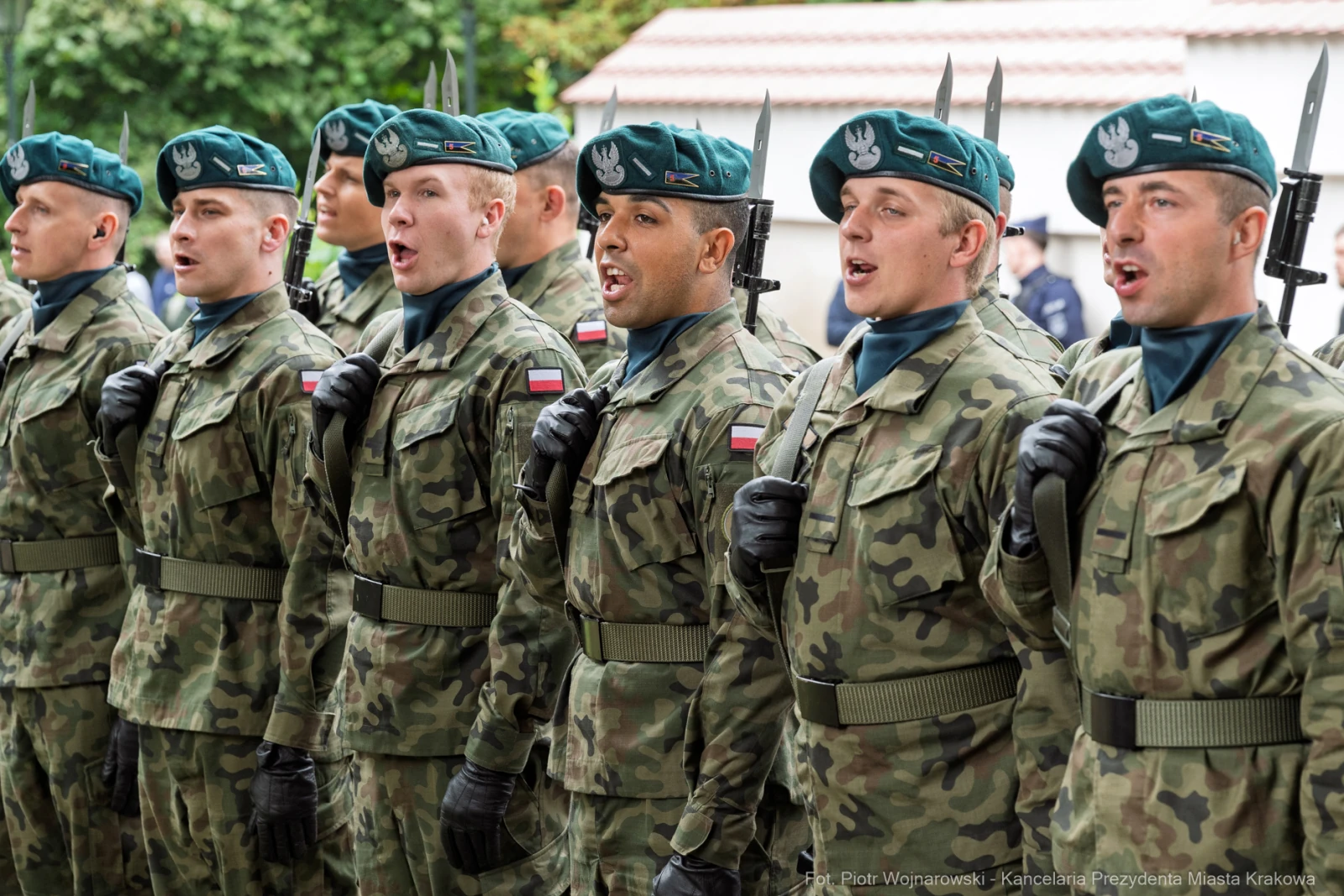 Żołnierze w mundurach wojskowych, śpiewający podczas ceremonii, z bronią w rękach.  Autor: Piotr Wojnarowski