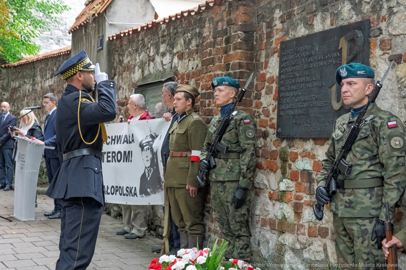 Ceremonia upamiętniająca z udziałem żołnierzy i flagi, z tablicą pamiątkową w tle.  Autor: Piotr Wojnarowski