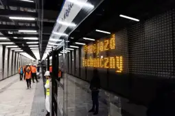 Nowoczesna stacja metra z pracownikami budowlanymi i wyświetlaczem informacyjnym.