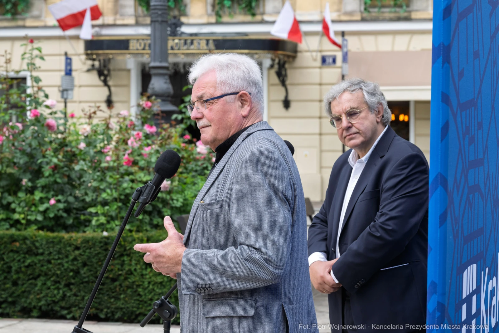 Dwaj mężczyźni przemawiają na tle flag i dekoracji miejskich.  Autor: Piotr Wojnarowski