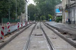 Tor tramwajowy w trakcie remontu, otoczony barierkami i z widocznymi pracami budowlanymi.