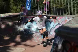Dziewczynka na rolkach wykonująca trik w skateparku.