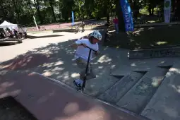 Chłopiec na hulajnodze wykonujący skok na skateparku.
