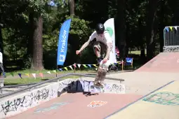 Skater wykonujący trik na deskorolce w parku.