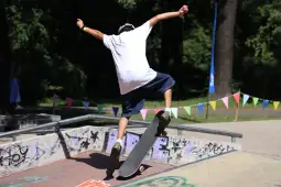 Skater wykonujący trik na desce w skateparku.