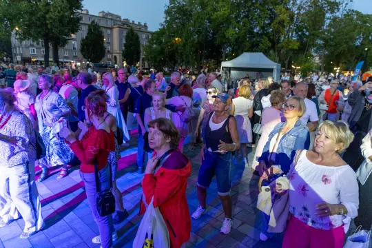 Tłum ludzi bawiący się na wydarzeniu plenerowym w miejskim parku.