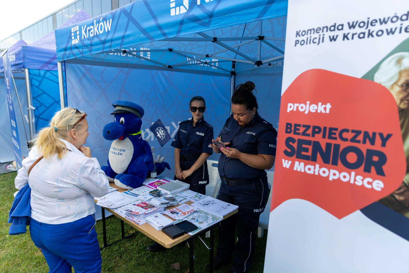 Stoisko informacyjne z policjantkami, maskotką i materiałami dla seniorów w Krakowie.  Autor: Bogusław Świerzowski